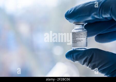 Montréal, CA - 4 mars 2021 : main dans un flacon de gants bleu contenant le vaccin Pfizer BioNTech Covid-19 Banque D'Images