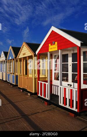 « Fairs Folly », un refuge de vacances peint en rouge vif et blanc dans une longue rangée de huttes de plage colorées bordant la Promenade et d'autres sites de bord de mer à Southwold, Suffolk, Angleterre, Royaume-Uni. Les cabines privées en bois verrouillables - environ 300 en tout - sont passées d'humbles cabanes traditionnelles de pêcheurs à des biens immobiliers très prisés et des symboles emblématiques des vacances au bord de la mer britannique, la plupart étant louées bien avant la saison des vacances. Les cabanes de plage qui viennent sur le marché peuvent vendre pour des sommes à six chiffres. Banque D'Images