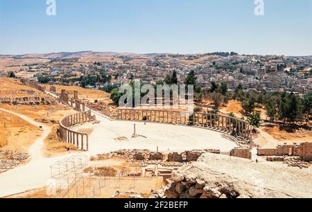 2000 Jerash Jordanie Moyen-Orient - le Forum ovale et Cardo Maximus dans l'ancien Jerash avec la ville moderne derrière. Jerash est considéré comme l'un des plus grands et des plus bien préservés sites de l'architecture romaine dans le monde en dehors de l'Italie. Les colonnes indiquent l'emplacement d'un stoa, ou d'un passage couvert, où les stalles des vendeurs à ciel ouvert peuvent être situées par mauvais temps. Après la conquête romaine en 63 av. J.-C., Jerash et les terres qui l'entourent ont été annexées à la province romaine de Syrie . Banque D'Images