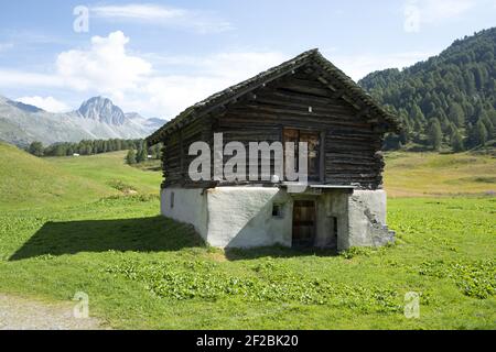 Chalet de montagne avec un lac de montagne en arrière-plan, avec vue panoramique sur la vallée de l'Engadin, en Suisse. Banque D'Images