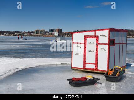 Cabane de pêche sous la glace avec des traîneaux et des pêcheurs qui forent le trou Baie de Kempenfelt du lac Simcoe gelée à Barrie, Canada Banque D'Images