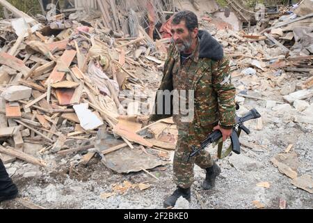 STEPANAKERT, HAUT-KARABAKH - NOVEMBRE 06 : un soldat de l'Armée de défense d'Artsakh marche dans l'épave d'une maison où trois personnes auraient été tuées dans une attaque à la roquette lancée par l'armée azérie à Stepanakert, capitale de facto de la République autoproclamée d'Artsakh ou du Haut-Karabakh, De jure partie de la République d'Azerbaïdjan le 06 novembre 2020. Les combats entre l'Arménie et l'Azerbaïdjan sur le Haut-Karabakh, également connu sous le nom de République d'Artsakh, ont rééclaté à la fin de septembre pour se transformer en une guerre de six semaines avec les deux pays s'accusant mutuellement de provocation qui a fait des milliers de morts. Banque D'Images