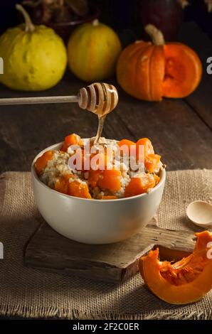 Porridge de millet, blé et riz à la citrouille, parsemé de miel sur un fond en bois de style sombre Banque D'Images