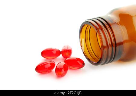 Comprimés de vitamine rouge en flacon isolé sur fond blanc Banque D'Images