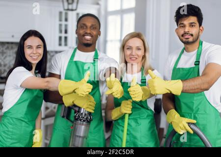 Des nettoyeurs multiraciaux souriants qui font des pouces Banque D'Images