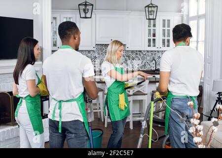 Assez confiante femme blonde de 40 ans, chef de l'équipe de nettoyage, donnant des ordres à chaque membre de son équipe, debout dans des appartements de luxe Banque D'Images