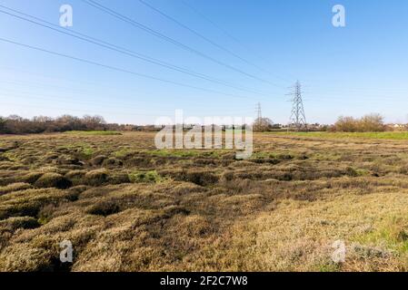 Inonder les marais de la rivière Roach à marée basse près de Rochford et Stambridge, Essex, Royaume-Uni. Pylône et fils électriques Banque D'Images