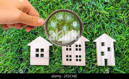 Realtor examine les maisons à travers une loupe. Examen du marché immobilier, recherche des meilleures offres basées sur les critères de prix, locat Banque D'Images