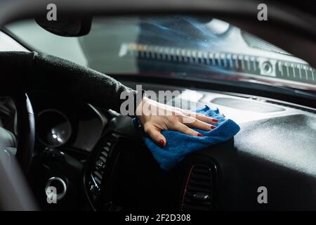 Main avec un chiffon microfibre bleu pour nettoyer l'intérieur de la voiture. Banque D'Images