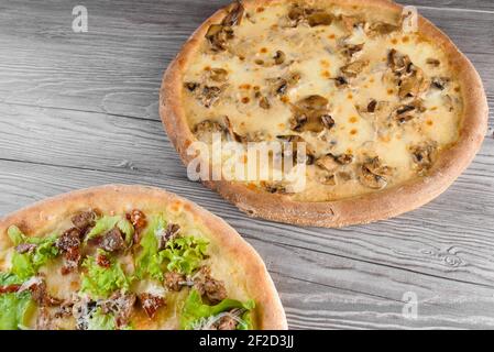 Assortiment de pizzas avec viande, prosciutto, tomates, mozzarella, parmesan, salade, champignons, sauce à la crème sur bois. Banque D'Images