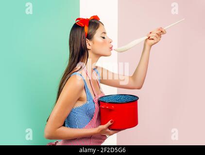 Femme de ménage drôle. Pinup femme cuisine dans la cuisine. Jolie fille de style vintage. Préparation des aliments. Banque D'Images