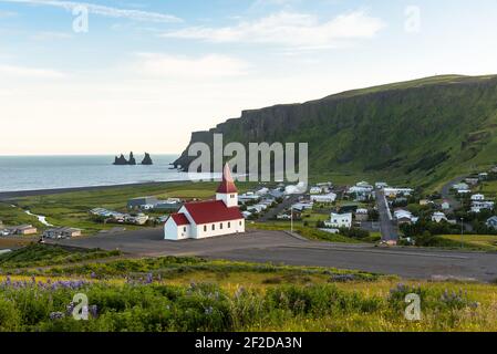 Belle vue sur la station balnéaire de Vik Islande en été. Une petite église est visible en premier plan. Banque D'Images