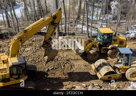 En construction d'une nouvelle route asphaltée. Les pelles hydrauliques, les niveleuses et les galets de roulement qui travaillent sur la nouvelle construction de routes Banque D'Images