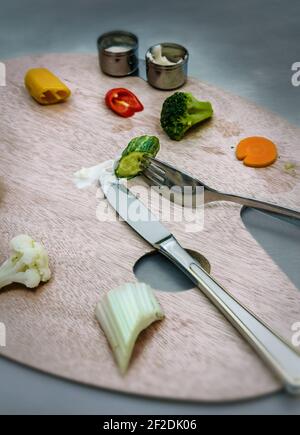 Palette en bois d'artiste sur laquelle les légumes sont placés. Dans les tasses il y a de la trempette de légumes. Un couteau et une fourchette. Banque D'Images