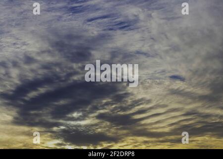 Avec un soleil couchant au-dessous d'eux, les nuages sont déchirés par le vent, dans un modèle de squelette de diverses nuances de gris et de blanc, avec quelques tirets o Banque D'Images