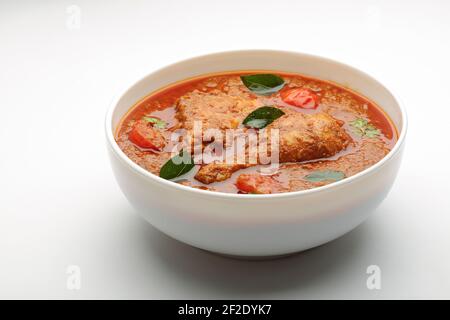 Curry de poulet ou masala, plat piquant de poulet rouge épicé garni de feuilles de coriandre et de piment vert frais qui est disposé dans un cera blanc Banque D'Images