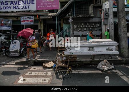 Les gens marchent devant un cercueil vide à l'extérieur d'un marché public pour rappeler aux gens de rester à la maison avant que le métro de Manille ne revienne à la quarantaine communautaire améliorée modifiée (MECQ) à Quezon City, Metro Manila, Philippines. Banque D'Images