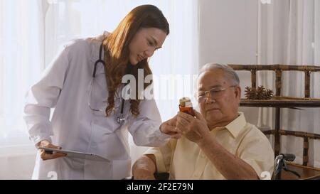 La jeune femme asiatique médecin prescrit des médicaments aux patients handicapés plus âgés sur fauteuil roulant lorsque le patient âgé de l'homme âgé a le temps de se rendre à Rentre à la maison. Médecine et h Banque D'Images