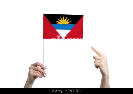 Une belle main femelle tient un drapeau d'Antigua-et-Barbuda à laquelle elle montre le doigt de son autre main, isolé sur fond blanc. Banque D'Images