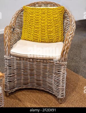 Une chaise en canne avec un siège rembourré et un coussin tissé jaune retour Banque D'Images