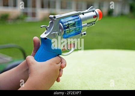 un enfant tient un pistolet en plastique avec les deux mains Banque D'Images