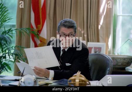 Le président Ronald Reagan porte des lunettes tout en travaillant à son bureau dans le bureau ovale. Banque D'Images