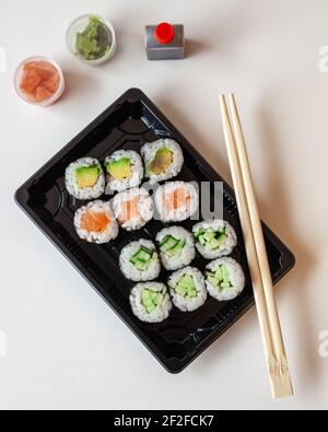 Vue de dessus des sushis japonais frais à emporter avec un bâton de hache, du gingembre mariné et du wasabi sur fond blanc avec espace pour les copies Banque D'Images