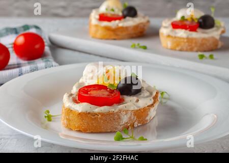 Bruschetta à la tomate, aux olives et à l'œuf de caille poché Banque D'Images