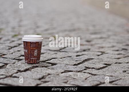 tasse à café jetable sur un sol pavé ville Banque D'Images