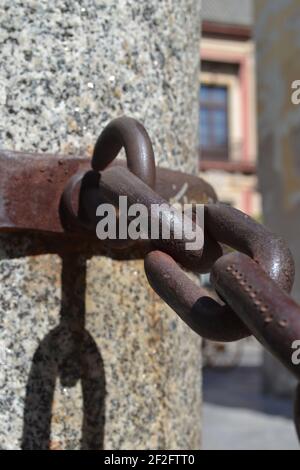 Chaînes de fonte et poste en marbre devant la cathédrale de Séville (Catedral de Séville), Andalousie, Espagne. Chaînes rouillées marron, poteau en marbre gris marbré. Banque D'Images