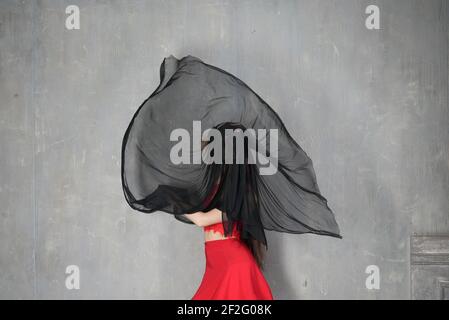 Femme danseuse, portrait avec visage couvert en mouvement en robe rouge avec un tissu dans le vent Banque D'Images