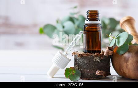 Bannière, concept de cosmétiques biologiques, bouteille en verre avec huile, pipette et feuilles d'eucalite sur fond de bois clair Banque D'Images