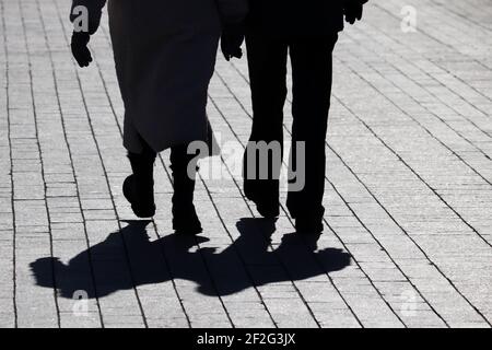 Couple marchant dans la rue, silhouettes et ombres de deux personnes sur le trottoir piétonnier. Jambes mâles et femelles, concept de relations Banque D'Images