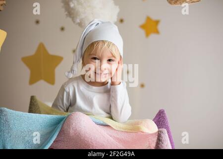 Enfant mignon, garçon blond, jouant la nuit avec une écharpe colorée et un ours en peluche Banque D'Images