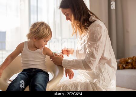 Petit enfant, garçon blond, injection dans la salle de consultation à partir de la pédiatrie, vaccination annuelle. Banque D'Images