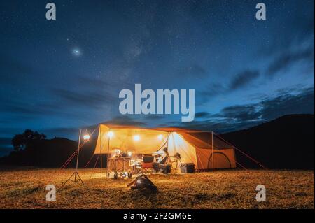 Touristes en tente jaune campant sur la colline avec la manière laiteuse dans le ciel nocturne au parc national Banque D'Images