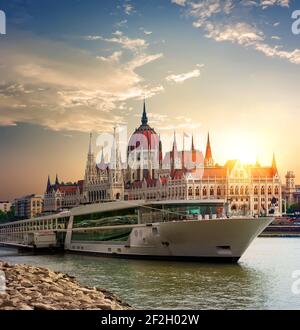 Coucher de soleil sur le Parlement hongrois et bateau touristique sur Danube Banque D'Images