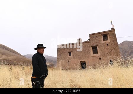 (210312) -- YUSHU, 12 mars 2021 (Xinhua) -- Nyima est vu à l'extérieur d'une maison tibétaine traditionnelle, qui était autrefois la maison d'un ancien responsable local dans le village de Lemda, canton de Lab du comté de Chindu, préfecture autonome tibétaine de Yushu, province de Qinghai, dans le nord-ouest de la Chine, le 9 mars 2021. Nyima, 40 ans, est né dans une famille d'éleveurs du comté de Chindu, Yushu. Son père est bien connu localement comme un artisan dans l'architecture tibétaine traditionnelle. Influencé par son père, Nyima a montré un grand intérêt pour l'architecture tibétaine traditionnelle depuis son enfance. En 2010, un violent tremblement de terre a secoué y Banque D'Images