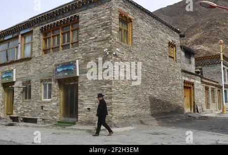 (210312) -- YUSHU, 12 mars 2021 (Xinhua) -- Nyima passe devant une maison tibétaine traditionnelle nouvellement construite dans le canton de Lab du comté de Chindu, préfecture autonome tibétaine de Yushu, province de Qinghai, dans le nord-ouest de la Chine, le 9 mars 2021. Nyima, 40 ans, est né dans une famille d'éleveurs du comté de Chindu, Yushu. Son père est bien connu localement comme un artisan dans l'architecture tibétaine traditionnelle. Influencé par son père, Nyima a montré un grand intérêt pour l'architecture tibétaine traditionnelle depuis son enfance. En 2010, un violent tremblement de terre a secoué Yushu et endommagé de nombreux bâtiments tibétains traditionnels, qui ont fait Banque D'Images