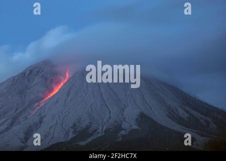 Sumatra Nord. 12 mars 2021. La photo prise le 12 mars 2021 montre des matériaux volcaniques et des fumées blanches qui se déversèrent du mont Sinabung, vues du village de Tigna Pancur à Karo, au nord de Sumatra, en Indonésie. Crédit: Alberth Damanik/Xinhua/Alamy Live News Banque D'Images