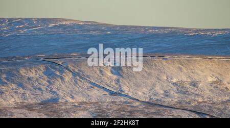 En fin d'après-midi, le soleil illumine la pente de montagne enneigée de Chapel Fell à Weardale, les Pennines du Nord, comté de Durham, Royaume-Uni Banque D'Images