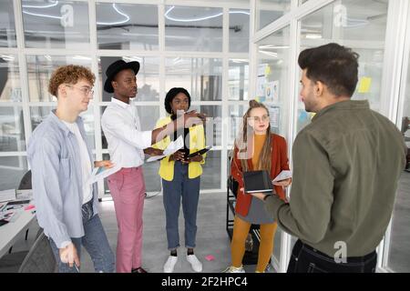 Cinq jeunes spécialistes DE L'INFORMATIQUE multiraciale hautement qualifiés avec projet d'analyse de gadgets au bureau Banque D'Images