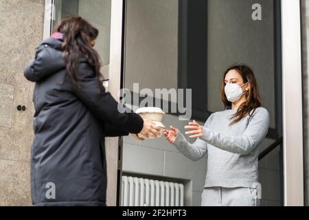 Voisin donnant de l'aide alimentaire de secours dans le masque facial Banque D'Images