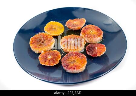 oranges assaisonnées de sel d'huile et de poivre sur un bleu fond blanc de la plaque Banque D'Images