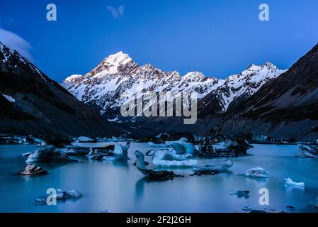 Soleil brillant sur la montagne enneigée massive du Mont Cook/Aoraki. Blocs de glace de forme différente flottant sur le lac Hooker, en Nouvelle-Zélande. Banque D'Images