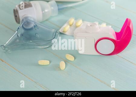 Kit d'inhalateur d'asthme, pilules anti-allergie et machine d'aérosol avec masque d'inhalateur, concept asthme et traitement sur fond vert, espace de copie. Banque D'Images