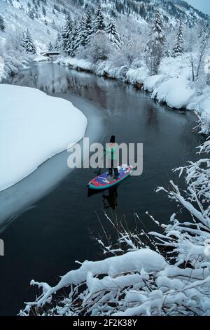 Femme paddleboard sur la rivière en hiver Banque D'Images