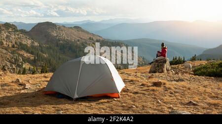 Femme campant avec un chien en montagne contre le ciel pendant les vacances Banque D'Images