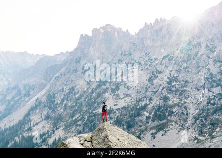 Vue arrière de la femme debout sur le rocher contre la montagne pendant randonnée en vacances Banque D'Images