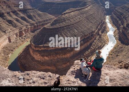 Femme assise avec un chien regardant la vue depuis la falaise à Parc national de Goosenecks pendant les vacances Banque D'Images